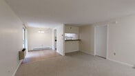 This 1-bedroom, 1-bathroom residence is thoughtfully laid out across a single floor, offering a comfortable and efficient use of space. The entry hall, flanked by louvered bifold closet doors, opens into a carpeted living area that flows naturally toward the rest of the unit. The combined kitchen and living room area serves as the heart of the home, featuring a peninsula with dark granite-style countertops that separates the kitchen from the main living space. The kitchen is equipped with white cabinetry fitted with brushed nickel hardware, matching white appliances including an electric range and refrigerator, and a dedicated pantry closet for added storage. The dining room, finished with light hardwood flooring, features a chandelier and a sliding glass door with vertical blinds that brings in natural light. The spacious bedroom offers generous double closet storage with louvered doors, plush carpeting, and a window with a view of surrounding greenery. The full bathroom is clean and bright, with white cabinetry, a single vanity with a white countertop, tile flooring, and a full tub-shower combination. Baseboard heating is present throughout, and neutral tones in every room create a calm, cohesive ambiance.