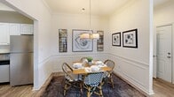 This two-story home in Knoxville, Tennessee offers a thoughtfully designed layout spread across two levels. The main floor welcomes you into a bright and open living room, where hardwood-style flooring, a ceiling fan, and neutral tones create a warm, inviting atmosphere. A staircase with a wood banister leads to the upper level. Adjacent to the living area, the dining room features classic wainscoting, crown molding, and elegant pendant lighting, complemented by a nearby closet for added convenience. The kitchen is outfitted with arched white cabinetry, dark countertops, a double stainless steel sink, and black appliances including a dishwasher and range. A dedicated in-unit laundry room provides full-size washer and dryer hookups along with overhead shelving. The primary bedroom is a spacious retreat with plush carpeting, a ceiling fan, and direct access to an en suite bathroom. Additional bedrooms are carpeted and well-lit, each featuring ceiling fans and windows that bring in natural light. A full bathroom with a tub-shower combination and hardwood-style flooring serves the remaining bedrooms. The primary suite also includes a generous walk-in closet with built-in wire shelving on multiple walls, offering ample storage throughout this comfortable Knoxville home.