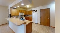 Located at 630 Ninth St N in La Crosse, Wisconsin, this single-floor unit offers a well-organized and practical layout designed for comfortable everyday living. The kitchen is a standout feature, equipped with warm oak cabinetry, generous counter space, recessed and flush-mount ceiling lighting, and a full suite of white appliances including an electric range, over-the-range microwave, dishwasher, and refrigerator. The kitchen opens toward the living and dining areas, creating a connected, sociable flow throughout the main living spaces. The living room is bright and welcoming, with large windows that invite natural light and provide views of the surrounding neighborhood. Tile flooring extends through the kitchen and main living areas, offering durability and ease of maintenance. The bedrooms are carpeted for comfort and include windows that allow for additional natural light. The primary bathroom is notably spacious, featuring dual vanities with oak cabinetry, two large mirrors with sconce lighting, tile flooring, and a separate water closet area with a window. A dedicated in-unit laundry area with a full-size washer and dryer and an overhead utility shelf adds practical convenience to this well-appointed unit.