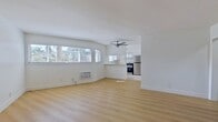 Located at 4143 Palmwood Dr, Unit 9, Los Angeles, CA 90008, this 600-square-foot, one-bedroom, one-bathroom unit offers a clean and modern living experience across a single floor. The open-concept living room and kitchen area is anchored by light wood laminate flooring, crisp white walls, and large windows fitted with horizontal blinds that allow ample natural light and views of surrounding palm trees. A ceiling fan provides additional comfort, and a wall-mounted A/C unit ensures year-round climate control. The kitchen features white cabinetry, light countertops, a stainless steel double-basin sink with a modern faucet, and a stainless steel gas range, all illuminated by a window overlooking the outdoors. The 140-square-foot bedroom continues the light wood flooring, includes a mirrored sliding closet, a ceiling fan with light fixture, a wall A/C unit, and windows that bring in natural light. The bathroom is outfitted with a full white tiled tub-shower combination and chrome fixtures. A hallway and entrance area complete the layout, offering a well-connected and efficient flow throughout the unit. The overall ambiance is bright, clean, and move-in ready.