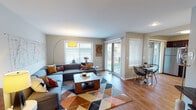 Located in St. Charles, IL, this single-floor residence on Covington Court offers a well-designed layout with modern finishes and a cohesive mid-century-inspired aesthetic throughout. The open-concept living area is bright and welcoming, featuring warm hardwood-style flooring, neutral wall tones, and a sliding glass door that allows abundant natural light and provides access to an outdoor patio. The spacious living room comfortably accommodates a large sectional sofa and features decorative wall art, creating an inviting atmosphere. The kitchen is a standout feature, appointed with rich dark wood cabinetry, light granite countertops, a classic subway tile backsplash, and a full suite of stainless steel appliances including a gas range, microwave, refrigerator, and dishwasher. A dedicated dining area sits adjacent to the kitchen, offering a functional and connected space for meals. The primary bedroom is a serene retreat with a bold accent wall, plush carpet, and a generous closet. A second bedroom provides additional flexibility with its own closet storage. The bathroom continues the home's cohesive design with dark wood cabinetry, granite countertops, a large vanity mirror, and hardwood-style flooring. This residence combines practical functionality with stylish, contemporary design details throughout.
