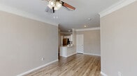 This well-designed 2-bedroom, 2-bathroom home in Austin, TX offers a comfortable and functional single-story layout. The open-concept living and dining area is anchored by light wood-look flooring, crown molding, and a ceiling fan, creating a bright and airy atmosphere. Large windows along the front of the living space invite natural light and provide views of the surrounding neighborhood. The kitchen features white cabinetry, granite countertops, stainless steel appliances including a refrigerator, and a peninsula with bar seating that seamlessly connects to the main living area. A louvered-door closet adds convenient storage near the entry. The spacious primary bedroom includes carpeted flooring, a ceiling fan, and a window for natural light. Its en-suite bathroom is appointed with a granite-topped double vanity, white shaker-style cabinetry, and wood-look flooring. The second bedroom also features carpet, a ceiling fan, and a built-in closet with louvered doors. A dedicated laundry room houses a full-size top-loading washer and dryer with overhead wire shelving. Crown molding and neutral warm-toned walls are consistent throughout, lending the home a cohesive and polished feel.
