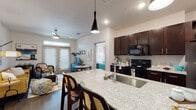 This single-story residence showcases a thoughtfully designed open-concept layout that seamlessly connects the kitchen, dining, and living areas. The kitchen is a standout feature, equipped with rich dark-wood cabinetry, granite countertops with a herringbone-tile backsplash, black appliances including a range and built-in microwave, and a spacious island with an undermount sink and pendant lighting overhead — ideal for both cooking and casual dining.

The living area offers a warm, inviting atmosphere with dark hardwood-style flooring, a ceiling fan, and French doors topped with a transom window that floods the space with natural light and provides outdoor access. The open sightlines between the kitchen and living room enhance the sense of space throughout.

Both bedrooms are generously sized, each featuring ceiling fans, large windows with ample natural light, and dark hardwood-style flooring. The primary bedroom connects to a well-appointed bathroom with granite vanity countertops, dark cabinetry, and a walk-in closet with built-in shelving. A full bathroom with a soaking tub and clean tile surround serves as an additional bath. The overall aesthetic is bright, modern, and cohesive throughout.