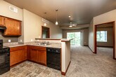 Located at 3500 Edgewood Rd NE in Cedar Rapids, Iowa, this single-floor, three-bedroom, two-bathroom home offers a functional and well-appointed layout. The open-concept kitchen flows seamlessly into the living area, creating a connected and sociable space. The kitchen features warm wood cabinetry, a double-basin sink, a dishwasher, a range, pendant lighting, and a peninsula that serves as both a workspace and a divider between the kitchen and living room. Stone-look tile flooring grounds the kitchen area, while plush carpeting carries throughout the living spaces and bedrooms. The living area is brightened by a sliding glass door that opens to an outdoor balcony and is equipped with a ceiling fan. The bedrooms are generously proportioned with large windows that frame views of surrounding greenery, providing ample natural light and a calm atmosphere. Rich wood-trimmed doors and baseboards add a cohesive, polished detail throughout the home. Three closets offer practical storage solutions. Both bathrooms are finished with stone-look tile flooring, wood vanities, white countertops, and full tub-shower combinations. A dedicated laundry room houses a full-size washer and dryer with overhead wire shelving for additional storage.