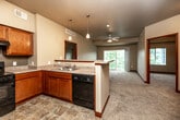 Located at 3500 Edgewood Rd NE in Cedar Rapids, Iowa, this single-floor, three-bedroom, two-bathroom home offers a functional and well-appointed layout. The open-concept kitchen flows seamlessly into the living area, creating a connected and sociable space. The kitchen features warm wood cabinetry, a double-basin sink, a dishwasher, a range, pendant lighting, and a peninsula that serves as both a workspace and a divider between the kitchen and living room. Stone-look tile flooring grounds the kitchen area, while plush carpeting carries throughout the living spaces and bedrooms. The living area is brightened by a sliding glass door that opens to an outdoor balcony and is equipped with a ceiling fan. The bedrooms are generously proportioned with large windows that frame views of surrounding greenery, providing ample natural light and a calm atmosphere. Rich wood-trimmed doors and baseboards add a cohesive, polished detail throughout the home. Three closets offer practical storage solutions. Both bathrooms are finished with stone-look tile flooring, wood vanities, white countertops, and full tub-shower combinations. A dedicated laundry room houses a full-size washer and dryer with overhead wire shelving for additional storage.