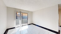 Located at 7111 N 75th Ave in Glendale, Arizona, this 2-bedroom, 1-bathroom single-floor residence offers a functional and refreshed living space. Throughout the main living and dining areas, large-format marble-look porcelain tile floors are accented by striking dark marble baseboard trim, creating a clean, polished aesthetic. The living area features a sliding glass door with vertical blinds that opens to an outdoor area, allowing natural light to pour in. A textured popcorn ceiling runs throughout the unit.

The kitchen is positioned toward the rear of the layout and features warm wood cabinetry and a practical design. The dining area flows naturally from the main living space, supporting an open and connected feel.

The bathroom is well-equipped, showcasing a rich wood-toned vanity with dark countertops, a large mirror, a combined tub and shower, and a built-in open shelving unit ideal for storage. The same distinctive marble-look tile and dark baseboard trim extend into this space.

The two bedrooms offer a contrast in flooring, with light wood-look laminate planks providing a warm, comfortable feel underfoot. Each bedroom includes a window with natural light, a wall-mounted HVAC unit, and a textured ceiling. The primary bedroom also includes a ceiling fan with light fixture. Both rooms provide a calm, neutral environment suitable for a variety of uses.