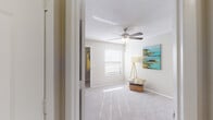 This single-story residence offers a well-organized layout that balances open living areas with private, functional spaces. The living room is a generous, light-filled area showcasing rich hardwood-style flooring, a ceiling fan, and a sliding glass door that opens to an outdoor balcony, allowing natural light to pour in. A breakfast bar with granite-style countertops connects the living area to the kitchen, creating an open, sociable flow ideal for everyday living and entertaining.

The kitchen is equipped with stainless steel appliances, including a refrigerator, range, and microwave, complemented by white cabinetry, a tile backsplash, and granite-style countertops. Directly accessible from the kitchen is a dedicated laundry room housing a full-size washer and dryer alongside a water heater, with wire shelving providing additional storage.

The bedrooms are carpeted for comfort, each featuring a ceiling fan and walk-in closet with built-in shelving for organized storage. Natural light enters through windows fitted with horizontal blinds. The bathrooms continue the hardwood-style flooring and include white vanity cabinetry with granite-style countertops, a tub-shower combination, and a large mirror. Throughout the residence, a neutral color palette and textured ceilings contribute to a clean, cohesive aesthetic.