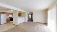 This single-floor unit offers a functional and comfortable layout designed to maximize everyday living. The welcoming living room is generously sized, featuring plush wall-to-wall carpeting, a large sliding glass door that fills the space with natural light, and direct access to an outdoor area. A dedicated entryway with a front door featuring a decorative transom window completes the welcoming arrival experience.

The kitchen is thoughtfully designed with warm oak cabinetry, ample counter space, and a convenient pass-through bar that connects it to the main living area. Appliances include a refrigerator, stove, and dishwasher, all set above tile flooring that extends into the adjacent utility area, where an in-unit washer and dryer are conveniently housed.

The bedrooms are well-proportioned, each featuring soft carpeting, ceiling fans, and windows that bring in natural light. The primary bedroom includes a sliding-door closet, while additional bedrooms offer flexible storage and living options.

The bathroom is cleanly finished with large-format tile flooring and a full soaking tub and shower combination set within a bright white surround. Throughout the unit, neutral tones, white walls, and wood-trimmed finishes create a cohesive and inviting ambiance.