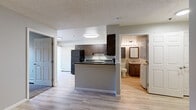 Located at 1175 Albion St in Denver's vibrant 80220 neighborhood, this one-bedroom, one-bathroom residence offers a well-designed single-floor layout that maximizes every square foot. Light wood-tone flooring runs throughout the main living areas, creating a clean, cohesive look, while a textured ceiling adds classic character overhead.

The kitchen is a functional highlight, featuring rich dark-walnut cabinetry, granite-style countertops, and a full suite of black appliances including a range, microwave, and refrigerator. A peninsula with breakfast-bar overhang opens directly to the living area, promoting an easy flow between cooking and entertaining. A sliding glass door fills the space with natural light and leads to a private balcony, framing outdoor views.

The bedroom is carpeted for comfort and includes a spacious sliding-door closet with built-in shelving and hanging rods. A window unit alongside baseboard heating ensures year-round climate control.

The bathroom is efficiently laid out with a warm wood vanity, mirrored medicine cabinet, and—notably—an in-unit stacked washer and dryer, adding exceptional convenience. Baseboard heaters are present throughout. Neutral gray walls and consistent finishes tie the entire unit together in a clean, move-in-ready aesthetic.