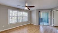 Located at 4659 Dawson Blvd in Atlanta, Georgia, this single-floor unit offers a clean, contemporary design throughout. Light hardwood flooring flows seamlessly across every room, complementing the neutral gray walls and crisp white trim that create a bright, cohesive aesthetic.

The main living area is a welcoming, well-lit space featuring a ceiling fan with a built-in light fixture, a large window with horizontal blinds that frames views of surrounding greenery, and a sliding glass door that opens to a private outdoor balcony. Natural light fills the room throughout the day, enhancing its open and airy feel.

The kitchen is thoughtfully designed with gray shaker-style cabinetry, white subway tile backsplash, light countertops, and stainless steel appliances including a dishwasher and refrigerator. A skylight-style overhead fixture provides bright task lighting, making the space both functional and visually appealing.

The bedrooms are comfortably sized, each featuring hardwood flooring, neutral walls, and windows with blinds that allow for natural light and privacy. The textured ceilings add a subtle architectural detail consistent throughout the unit.

The bathroom is finished with large-format gray tile surrounding a full soaking tub and shower combo, paired with a gray vanity featuring gold hardware and wood-look flooring, striking a balance between modern and warm design sensibilities.