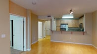 This two-floor residence offers a well-designed layout that balances open communal spaces with comfortable private areas. The main living area is anchored by warm hardwood flooring and neutral earth-toned walls, creating an inviting atmosphere throughout. A ceiling fan with integrated lighting adds both function and style to the spacious living room, which also benefits from track lighting along the kitchen-side wall.

The kitchen is thoughtfully designed with light maple cabinetry, granite countertops, and stainless steel appliances including a refrigerator, range, and built-in microwave. A raised breakfast bar with granite overhang provides casual seating and visually connects the kitchen to the living space in an open-concept fashion.

The bathrooms are well-appointed, featuring tile flooring, granite-topped vanities with wood cabinetry, and glass-enclosed shower-tub combinations. The primary bathroom offers additional space with both a soaking tub and a separate glass-enclosed shower, complemented by recessed lighting and tiled surrounds.

Bedrooms are carpeted for comfort and include mirrored sliding closet doors with built-in shelving systems. A set of sliding glass doors leads to a private balcony with views of greenery, allowing natural light to filter in through vertical blinds. The overall ambiance is clean, functional, and move-in ready.