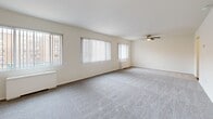 This one-bedroom, one-bathroom residence on Columbia Pike in Arlington, Virginia offers a practical and comfortable layout across a single floor. Upon entry, the space opens into a well-organized floor plan that includes a dedicated dining area, kitchen, and generous living space. The bedroom is notably spacious, featuring plush carpeting, two large windows dressed with vertical blinds that allow ample natural light, and a ceiling fan for year-round comfort. The bedroom also benefits from two closets, including a walk-in closet outfitted with built-in shelving and hanging rods, providing substantial storage capacity. The bathroom is finished with elegant marble-patterned tile surrounding a full soaking tub, lending a clean and polished aesthetic. The kitchen and bathroom areas feature wood-style flooring, while soft carpeting runs throughout the living and bedroom spaces. The living area is open and airy, illuminated by multiple windows offering views of the surrounding neighborhood. Neutral wall tones and clean white ceilings throughout create a bright, cohesive atmosphere. The overall design prioritizes functionality while maintaining a comfortable, welcoming ambiance suitable for everyday living in the heart of Arlington.