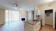 This single-story residence offers a cohesive, modern design highlighted by light wood-style flooring and neutral warm tones carried consistently throughout every room. The open-concept living and dining area serves as the central gathering space, anchored by a white-mantled fireplace and a ceiling fan overhead. Large vertical blinds along a full-width sliding door flood the area with natural light while providing outdoor access.

The kitchen is thoughtfully laid out in a galley-style configuration, featuring white shaker cabinetry with brushed nickel hardware, dark quartz countertops, a peninsula with an undermount stainless steel sink, and a full suite of stainless steel appliances including a refrigerator, range, microwave, and dishwasher. A tiled backsplash adds a refined finishing detail.

The bedrooms are generously proportioned, each equipped with a ceiling fan and windows fitted with horizontal blinds that allow natural light. Crown molding accents the living areas, adding an elevated architectural touch.

The bathrooms maintain a consistent design language, offering white vanity cabinetry with dark countertops, undermount sinks, framed mirrors, and soaking bathtubs with tiled surrounds. Light wood-style flooring extends into the bathrooms, unifying the overall aesthetic of the space.