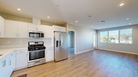 Located at 3909 Voltaire Street in San Diego's vibrant Ocean Beach neighborhood, this well-designed two-bedroom, one-bathroom home offers a thoughtful single-floor layout with contemporary finishes throughout. Light wood-style flooring flows seamlessly across every room, complementing the neutral gray and beige tones on the walls to create a clean, cohesive aesthetic.

The open-concept kitchen and living area serves as the heart of the home. The kitchen is outfitted with white shaker cabinetry, light countertops, and a full suite of stainless steel appliances including a gas range, built-in microwave, refrigerator, and dishwasher. A window above the sink brings in natural light, enhancing the bright and functional workspace.

The living area is generously proportioned and flows naturally from the kitchen, with recessed lighting overhead and access to an outdoor balcony through sliding glass doors, framing views of the surrounding San Diego landscape.

Both bedrooms feature ceiling fans, ample natural light, and outdoor views through large windows. The spacious primary bedroom includes sliding glass door access to the balcony. A hallway connects the bedrooms to the full bathroom, which features a glass-enclosed walk-in shower with white tile surround. The home's efficient layout and modern finishes make it a comfortable and practical residence.