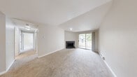 Located in Kent, Washington, this two-bedroom, two-bathroom residence offers a thoughtfully designed single-floor layout with a clean, neutral aesthetic throughout. The living room is a standout space, featuring soaring vaulted ceilings, plush carpeting, a tile-surround fireplace, and a sliding glass door that opens to a private balcony with views of surrounding greenery. Baseboard heating is present throughout, ensuring year-round comfort. The kitchen is well-appointed with white shaker-style cabinetry, light countertops, stainless steel appliances including a refrigerator and range, a stainless sink, and wood-look flooring that adds warmth and easy maintenance. Both bedrooms are carpeted and receive natural light through windows overlooking lush outdoor scenery, with the generously sized primary bedroom offering a comfortable retreat. The two bathrooms are finished with wood-look flooring, white vanities with light countertops, and brushed nickel hardware; one features a full tub-shower combo with white tile surround, while the second is a functional three-quarter bath. A hallway connects the main living areas, providing a practical flow throughout the home. The overall ambiance is bright, clean, and move-in ready.