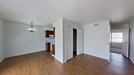This single-floor, 2-bedroom, 1-bathroom residence offers a practical and efficient layout designed to maximize the use of its compact footprint. The combined kitchen and living room area serves as the central hub of the home, with warm wood-look flooring running throughout. The living room receives natural light through large windows fitted with blinds, and is accented by a chandelier light fixture that adds a modest decorative touch. An open sightline connects the living area to the galley-style kitchen, which features dark wood cabinetry, light-toned countertops, a white electric range, refrigerator, and a double-basin sink — providing all essential cooking amenities in a well-organized, corridor layout.

Both bedrooms are carpeted for comfort and are served by a shared hallway. The primary bedroom includes a spacious sliding-door closet and a window that brings in natural light. The second bedroom is similarly bright and well-proportioned, with its own window. A dedicated hallway connecting the rooms also provides access to two closets, offering practical storage solutions.

The single bathroom features a wood-vanity with a light countertop, a toilet, and a full tub-shower combination with clean white surrounds. Wood-look flooring continues here, maintaining a consistent aesthetic throughout the home.