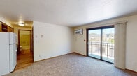 Located at 1670 Western Avenue in Green Bay, Wisconsin, this one-bedroom, one-bathroom unit offers a practical and functional single-floor layout. The living room is carpeted and features a sliding glass door that opens to a private balcony, allowing natural light to fill the space and providing outdoor views of the surrounding area. A wall-mounted air conditioning unit and a baseboard heating system ensure year-round comfort. The bedroom is a well-proportioned retreat, featuring plush carpeting, a large window that brings in natural daylight, and a baseboard heater. A closet with sliding wood-paneled doors provides ample storage and also houses the water heater. The full bathroom is finished with light wood-style flooring, a wood-toned vanity with a single sink, and a full tub-shower combination. The kitchen connects directly from the bedroom area and is equipped with standard appliances including a refrigerator. Throughout the unit, warm wood-toned trim and door frames add a consistent design detail, while the neutral, light-colored walls create a clean and open atmosphere. The overall layout is efficient and well-organized, making practical use of the available space.