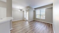 Located at 2720 S Highland Ave in Lombard, IL, this 2-bedroom, 3-bathroom residence offers a thoughtfully designed single-floor layout with modern finishes throughout. The open living and dining area is bathed in natural light from multiple windows with exterior views, complemented by warm wood-style plank flooring and a decorative pendant light fixture. A hallway connects the living space to the kitchen and private rooms, creating a logical and efficient flow. The kitchen is well-appointed with white shaker cabinetry, a mosaic tile backsplash, white quartz countertops, and a full suite of stainless steel appliances including a refrigerator, range, microwave, and dishwasher. Both bedrooms feature plush carpeting and ceiling fans; the primary bedroom is generously sized and includes access to a walk-in closet with built-in wire shelving. The three bathrooms are finished in a consistent, clean aesthetic with white vanities, quartz countertops, tiled tub-shower combinations with mosaic accent borders, and wood-style flooring. Neutral gray-toned walls carry throughout the unit, contributing to a calm, cohesive ambiance that suits a variety of interior styles.