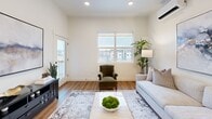 This thoughtfully designed 2-bedroom, 1-bathroom residence offers a well-organized single-level layout with a clean, contemporary aesthetic. The open-concept kitchen and living area serves as the heart of the home, where light wood cabinetry, white quartz countertops, stainless steel appliances — including a French door refrigerator and electric range — and a peninsula with pendant lighting create a functional and visually appealing space. Warm hardwood-style flooring runs throughout the main living areas, complementing the bright, neutral color palette.

The living room receives ample natural light through large windows overlooking the surrounding neighborhood, and features a wall-mounted mini-split system for climate control. A glass door provides access to the private balcony, extending the living space outdoors.

The primary bedroom is spacious, benefiting from multiple windows with outdoor views, plush carpeting, and a sliding-door closet. The second bedroom is equally well-lit with tall ceilings and a high-placed window for added privacy. The shared full bathroom is finished with a light wood vanity, white quartz countertop, a wide mirror, and hardwood-style flooring, maintaining the cohesive modern style found throughout the residence.
