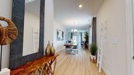 Located at 167 Privilege Rd in Bloomfield, Connecticut, this two-floor home is designed with a thoughtful layout that balances open, connected living spaces with comfortable private retreats. The main level greets you with a wide, light-filled entryway featuring hardwood-style flooring that flows seamlessly through the dining area and into the living room. The dining space is anchored by an elegant chandelier and opens toward a generously sized living room, which benefits from abundant natural light and direct access to an outdoor balcony through sliding glass doors. The kitchen is outfitted with contemporary flat-front cabinetry in a warm taupe finish, stainless steel appliances including a gas range, built-in microwave, and French door refrigerator, complemented by white quartz countertops and a decorative tile backsplash. A bright breakfast nook with large windows and a charming chandelier provides a casual dining option adjacent to the kitchen. Upstairs, the bedrooms are carpeted and serene, with the primary bedroom offering a walk-in closet and ample natural light. A full bathroom features large-format tile surround, a soaking tub, and modern vanity. An additional flexible room on the upper level, finished with plush carpet and double doors, serves well as a home office or guest space. Throughout, the home maintains a clean, neutral palette with warm accents.