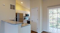 Located at 3900 Suffolk Dr in Dublin, Ohio, this single-floor residence offers a well-designed layout with functional living spaces throughout. The kitchen is a standout feature, equipped with stainless steel appliances including a refrigerator, electric range, and over-the-range microwave. White raised-panel cabinetry provides ample storage, while granite countertops extend across the workspace and onto a peninsula with a modern brushed-gold faucet — creating a natural division between the kitchen and the adjoining carpeted living area. A sliding glass door in the living space invites natural light and provides outdoor access. The bedrooms are generously proportioned with plush carpeting, vaulted or standard ceilings depending on the room, and windows that bring in natural light. Closet space is well-represented, with at least one bedroom offering a walk-in closet with built-in shelving. The bathrooms are finished in a clean, neutral palette featuring white cabinetry, white countertops, brushed nickel fixtures, and wood-look flooring. One bathroom includes a full tub-shower combination, while another serves as a half bath with a single vanity. Overall, the space presents a comfortable and practical design with consistent finishes throughout.