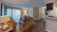 Located at 5300 New Centre Dr in Wilmington, NC, this single-floor residence offers a thoughtfully designed layout with modern finishes and a vibrant interior color palette throughout. The living room serves as the heart of the home, featuring rich hardwood-style flooring, a textured ceiling, and a sliding glass door that opens to a private balcony overlooking lush outdoor scenery, allowing natural light to fill the space. Adjacent to the living area, the dining room makes a bold statement with a warm orange accent wall and wood-style flooring, creating an inviting setting for entertaining. The kitchen is equipped with dark cabinetry, granite-style countertops, a stainless steel sink, and black appliances, with convenient access to a dedicated laundry area housing an in-unit Whirlpool washer. The two bedrooms are carpeted for comfort and each feature bold accent walls — one in striking yellow and another in warm orange — paired with natural light from windows with blinds and curtains. The bathrooms are clean and functional, each offering a shower-tub combination, with one showcasing dark cabinetry, a white countertop vanity, and hardwood-style flooring. The space combines contemporary design details with practical amenities for comfortable everyday living.