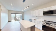 Located on the fifth floor at 304 Persimmon St in Peoria, IL, this 2-bedroom, 3-bathroom unit offers a well-designed single-level layout with a clean, modern aesthetic throughout. Light wood flooring flows consistently across all rooms, complemented by neutral warm-toned walls and recessed lighting.

The kitchen is a standout feature, outfitted with white shaker-style cabinetry, quartz countertops, stainless steel appliances including a French door refrigerator, electric range, built-in microwave, and dishwasher, along with a central island with pendant lighting — ideal for both cooking and casual dining.

Both bedrooms are comfortably sized, each featuring ceiling fans, windows with outdoor views, and easy closet access. The primary bedroom connects to a dedicated bathroom and a generously proportioned walk-in closet with wire shelving systems for organized storage. The additional closet provides further storage capacity.

All three bathrooms are finished with white vanities, quartz countertops, large mirrors, and light wood flooring. One bathroom includes a full soaking tub with an overhead shower. The hallway connects the rooms efficiently, contributing to a practical and flowing floor plan. The overall ambiance is bright, clean, and move-in ready.
