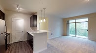 This single-floor residence offers a thoughtfully designed layout that balances functionality with comfort. The open-concept kitchen and living area form the heart of the home, where a galley-style kitchen impresses with dark espresso cabinetry, white countertops, stainless steel appliances including a range, microwave, and refrigerator, and hardwood-style flooring. A breakfast bar peninsula with pendant lighting above creates a natural transition into the spacious living area, which is finished with plush carpeting and leads to a private balcony through a large sliding glass door, flooding the space with natural light and offering pleasant outdoor views.

The bedrooms are generously proportioned, each featuring soft carpeting, neutral toned walls, and ceiling fans for year-round comfort. Ample closet space is accessible directly from the bedrooms, enhancing storage options. The bathroom is appointed with dark vanity cabinetry, white countertops, a well-lit mirror with modern fixtures above, hardwood-style flooring, and a clean, all-white walk-in shower enclosure with chrome accents. A dedicated walk-in closet adjacent to the bathroom adds further convenience. The overall ambiance is modern and neutral, providing a versatile, move-in ready living environment.