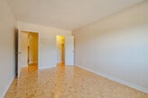 Located at 190 Cedar St in Cambridge, Ontario, this 2-bedroom, 1-bathroom unit offers a practical and well-organized single-floor layout. Warm parquet flooring is a consistent design element throughout the living spaces and bedrooms, lending a classic character to the interior. Neutral grey walls complement the light tones of the flooring, creating a clean and cohesive aesthetic throughout.

The combined kitchen and living area forms the heart of the unit. The kitchen features white cabinetry, white appliances including a stove and refrigerator, and tile flooring. A peninsula counter provides a natural transition into the dining area, which is accented by a pendant light fixture. The adjacent living room is bright and spacious, with a large sliding window that draws in natural light and offers outdoor views of surrounding greenery.

Both bedrooms feature the same warm parquet flooring and neutral walls. The primary bedroom includes a window with views of mature trees, a baseboard heater, and ample space. The second bedroom also includes closet storage. The full bathroom is finished with tile flooring, a tiled tub-shower combination, and a white vanity, offering a clean and functional design.