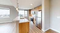 Located at 508 51st St in West New York, NJ, this well-appointed 2-bedroom, 2-bathroom residence offers a thoughtfully designed single-floor layout with a clean, contemporary aesthetic throughout. Light wood-tone flooring flows seamlessly across the living areas and bedrooms, complementing the neutral warm-gray walls and crisp white trim.

The open-concept kitchen is a standout feature, equipped with stainless steel appliances including a refrigerator, range, and built-in microwave. Warm wood cabinetry extends to the ceiling for ample storage, while a large central island with a white countertop and an integrated sink provides both workspace and casual dining. Pendant lighting adds a modern finishing touch above the island, and expansive windows flood the kitchen with natural light.

Both bedrooms are generously proportioned, each featuring large windows that frame impressive views of the surrounding cityscape and the New York City skyline in the distance. The primary bedroom offers a comfortable layout with a built-in closet. Wall-mounted HVAC units ensure individual climate control in each bedroom.

The two bathrooms are finished with light tile flooring and wood-toned vanity cabinetry. One bathroom features a glass-enclosed walk-in shower, while the second includes a full soaking tub with a handheld showerhead and accessibility grab bars. Both are clean, functional, and well-lit.