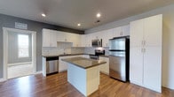 This single-floor unit offers a thoughtfully designed layout that balances functionality and modern style throughout. The kitchen serves as a standout feature, showcasing crisp white cabinetry, a classic subway tile backsplash, dark quartz countertops, and a full suite of stainless steel appliances including a refrigerator, range, built-in microwave, and dishwasher. A central island provides additional prep space and adds to the open, airy feel of the area, which is grounded by warm hardwood-style flooring.

The two bedrooms are carpeted for comfort and brightness, each offering natural light through well-placed windows. The primary bedroom features a ceiling fan, a dual-window accent wall with a charming gray feature wall, and access to a generous walk-in closet equipped with multiple hanging rods and shelving. The second bedroom is equally well-lit, with a large window and direct sightlines to the kitchen.

Two full bathrooms serve the unit, both finished with white cabinetry, dark countertops, and combination tub-shower units. One bathroom features tile flooring and a large vanity mirror, while the other offers a clean, streamlined design with light vinyl flooring. The overall aesthetic throughout the unit is clean, contemporary, and move-in ready.