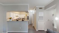 Located at 11355 Richmond Ave in Houston, TX 77082, this single-floor residence offers a thoughtfully designed layout that balances functionality and comfort. The open-concept kitchen is a standout feature, equipped with white shaker-style cabinetry, granite-style countertops, a subway tile backsplash, and stainless steel appliances including a refrigerator and electric range. A peninsula breakfast bar connects the kitchen to the main living area, creating an ideal space for casual dining and entertaining. Crown molding and dark hardwood-style flooring carry throughout the main living areas, lending a cohesive and polished look. The living room is bright and welcoming, featuring multiple windows with exterior door access that bring in natural light and provide outdoor connectivity. The bedroom is a calm retreat with carpeted flooring, vaulted ceilings, and a spacious walk-in closet. The bathroom is generously sized, showcasing white cabinetry, dual vanity mirrors, stone-look countertops, and a large vanity with ample storage. A dedicated in-unit laundry area adds everyday convenience. Overall, the space presents a clean, neutral palette with modern finishes throughout.