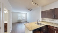 Located at 103 S Wood Ave in Linden, NJ, this two-bedroom, one-bathroom unit offers a practical and well-appointed single-floor layout. The open-concept living and kitchen area is anchored by a peninsula with granite countertops and a stainless steel sink, providing both workspace and a natural dividing line between the kitchen and living space. The kitchen is outfitted with rich dark-brown cabinetry, a tile mosaic backsplash, and a full suite of black appliances including a range, microwave, dishwasher, and refrigerator. The living area features warm hardwood-style flooring, a ceiling fan with light fixture, a wall-mounted HVAC unit, and a window that lets in natural light. Both bedrooms continue the hardwood-style flooring and neutral wall tones, with the primary bedroom offering a comfortable footprint. The second bedroom includes a window with blinds and a wall-mounted HVAC unit. The bathroom is finished with light rectangular tile flooring, dark wood cabinetry with a vanity, and grab bar support. Clean white trim and panel-style doors are consistent throughout, giving the unit a cohesive, modern aesthetic.