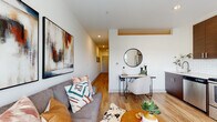 Located at 531 Grand Blvd in Kansas City, Missouri, this single-floor residence offers a well-designed open-concept layout that seamlessly connects the kitchen, dining, and living areas. The kitchen is equipped with a full suite of stainless steel appliances, including a range, over-the-range microwave, dishwasher, and a French door refrigerator. Rich dark-toned cabinetry lines the walls and pairs with a classic white subway tile backsplash and light countertops, creating a striking visual contrast. Light wood-style flooring runs throughout the entire unit, lending warmth and continuity to each space. The living area provides a comfortable and stylish retreat, complemented by recessed lighting and room for a dedicated workspace or dining nook. A long hallway connects the main living spaces to the private bedroom, which features elevated ceilings with a clerestory window that draws in natural light from above, a ceiling fan, and a calm, neutral palette. The bathroom is cleanly appointed with dark cabinetry, a vanity, and matching wood-style flooring that echoes the rest of the unit. The overall ambiance is modern, cohesive, and thoughtfully finished, making this Kansas City residence a functional and inviting living space.