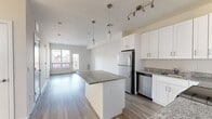 Located at 71 Connecticut Ave in Norwalk, CT, this 2-bedroom, 2-bathroom residence offers a thoughtfully designed single-floor layout that maximizes comfort and functionality. The open-concept living and kitchen area serves as the heart of the home, where light hardwood-style flooring flows seamlessly throughout. The kitchen is well-appointed with white shaker cabinetry extending to the ceiling, granite countertops, a central island with additional counter space, stainless steel appliances including a refrigerator, range, microwave, and dishwasher, and pendant lighting that adds a modern touch. The living area opens toward glass doors that lead to a balcony, allowing ample natural light to fill the space. Both bedrooms are generously sized, each featuring large windows that frame outdoor views of the surrounding Norwalk neighborhood. The primary bedroom offers a comfortable footprint with excellent natural light. The two bathrooms are finished in a clean, contemporary style, each equipped with white shaker vanities, quartz or solid-surface countertops, large mirrors, and light wood-tone flooring. One bathroom features a glass-enclosed shower, while the other includes a tub-shower combination with white tile surround. A dedicated closet provides additional storage. The overall aesthetic is bright, modern, and move-in ready.