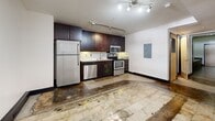This 2-bedroom, 1-bathroom unit at 50 West Fourth St. in Winston-Salem, NC showcases an industrial-modern design throughout. Polished concrete floors flow across the open-concept living and kitchen area, where dark espresso cabinetry, granite countertops, stainless steel appliances, and track lighting create a sleek culinary space. The bedrooms are bright and functional, with windows inviting natural light. The bathroom features a full tub-shower combo, tile flooring, and a dark-finished vanity with a glass countertop. A painted exposed-brick hallway and bold black door frames reinforce the building's urban character.