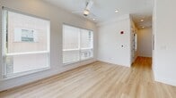 Located in the heart of Dallas's East Village neighborhood at 2217 N Fitzhugh Ave, this single-floor unit offers a thoughtfully designed layout that maximizes every square foot. The space is defined by clean, contemporary finishes and an open feel throughout.

The kitchen is a standout feature, showcasing tall white cabinetry that extends nearly to the ceiling, dark contrasting countertops, and a full suite of stainless steel appliances including a refrigerator, range, built-in microwave, and dishwasher. A central island with matching dark countertop provides additional prep space and casual dining potential, while a trio of globe pendant lights adds a warm, stylish focal point. A classic white subway tile backsplash and a large window bathe the kitchen in natural light.

The living area is bright and airy, with light-toned luxury vinyl plank flooring running throughout, recessed lighting, and a ceiling fan. Oversized windows with blinds invite generous natural light while maintaining privacy.

The bathroom is finished in a crisp, modern palette featuring large-format white wall tiles, a full soaking tub with a chrome combination showerhead, and coordinating tile flooring. The overall ambiance of the space is clean, minimalist, and move-in ready.