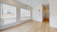 Located in the heart of Dallas's East Village neighborhood at 2217 N Fitzhugh Ave, this single-floor unit offers a thoughtfully designed layout that maximizes every square foot. The space is defined by clean, contemporary finishes and an open feel throughout.

The kitchen is a standout feature, showcasing tall white cabinetry that extends nearly to the ceiling, dark contrasting countertops, and a full suite of stainless steel appliances including a refrigerator, range, built-in microwave, and dishwasher. A central island with matching dark countertop provides additional prep space and casual dining potential, while a trio of globe pendant lights adds a warm, stylish focal point. A classic white subway tile backsplash and a large window bathe the kitchen in natural light.

The living area is bright and airy, with light-toned luxury vinyl plank flooring running throughout, recessed lighting, and a ceiling fan. Oversized windows with blinds invite generous natural light while maintaining privacy.

The bathroom is finished in a crisp, modern palette featuring large-format white wall tiles, a full soaking tub with a chrome combination showerhead, and coordinating tile flooring. The overall ambiance of the space is clean, minimalist, and move-in ready.
