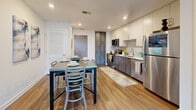 Located on the 7th floor at 120 Piedmont Ave NE in downtown Atlanta, this well-appointed apartment offers four bedrooms and four bathrooms across a thoughtfully designed single-floor layout. The open-concept living and dining area flows seamlessly from the kitchen toward floor-to-ceiling windows, flooding the space with natural light and framing views of the Atlanta skyline. A ceiling fan accents the living area, adding both style and comfort.

The kitchen is outfitted with stainless steel appliances, including a refrigerator, range, and built-in microwave, complemented by two-tone cabinetry featuring white upper cabinets and wood-grain lower cabinets, a subway tile backsplash, and clean white countertops. Warm hardwood-style flooring runs throughout the main living areas, adding continuity and a modern aesthetic.

Each of the four bedrooms offers a comfortable, private retreat, with select rooms showcasing exposed concrete ceilings and walls that lend an industrial character to the space. The bedrooms are well-sized and include ample closet storage. The four bathrooms feature tiled tub-shower combinations with clean white subway tile surrounds and wood-toned vanities with white countertops. A dedicated laundry area and hallway complete the floor plan, making this apartment a functional and stylish urban residence.