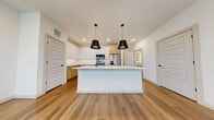 This 1,360 sq ft two-story home in Argyle, TX features 3 bedrooms, 3 bathrooms, and 2 closets across two floors. The main level (480 sq ft) offers an open-concept kitchen and living area with light hardwood flooring, recessed lighting, and large windows. The kitchen showcases two-tone cabinetry, quartz countertops, a center island with pendant lighting, tile backsplash, and stainless steel appliances. Upstairs (880 sq ft), the 170 sq ft primary bedroom includes a walk-in closet and a spa-like ensuite with dual vanity, soaking tub, glass shower, and black hardware accents. Additional bedrooms feature plush carpet and ceiling fans.
