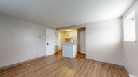 Located at 90 Edbert St in Chicopee, MA, this single-floor apartment offers a practical and well-organized layout suited for comfortable everyday living. The open-concept living and dining area features warm wood-look laminate flooring, neutral-toned walls, and a textured ceiling. A baseboard heating unit runs along the wall, and a window allows natural light to filter in, enhancing the sense of space. The kitchen is efficiently designed with white cabinetry, a marble-style countertop peninsula that doubles as a breakfast bar, and essential appliances including a coil-burner electric range with overhead ventilation and a full-size top-freezer refrigerator. A closet adjacent to the kitchen provides additional storage. The bedroom is a quiet, dedicated space with the same laminate flooring, a wall-mounted air conditioning unit for climate control, a baseboard heater, and a window with blinds offering natural light. The bathroom is clean and functional, featuring a shower/tub combo, a white vanity with under-sink storage, a medicine cabinet mirror, and wood-look flooring that ties the space together. Overall, the apartment presents a tidy, move-in-ready environment with consistent finishes throughout.