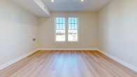 This single-floor unit at 755 Morton St E in Boston's Mattapan neighborhood presents a clean, modern aesthetic throughout its thoughtfully arranged layout. Light hardwood flooring flows continuously across every room, lending a cohesive and airy feel to the entire space.

The kitchen is a standout feature, outfitted with crisp white shaker-style cabinetry, light quartz countertops, and a full suite of stainless steel appliances including a range, microwave, refrigerator with ice maker, and dishwasher. A gold-toned faucet adds a refined accent against the clean white backdrop. A louvered closet door nearby provides convenient storage access.

The living area is generously proportioned for the overall footprint, with recessed lighting and a decorative gold sputnik-style fixture near the entry, which also features a utility panel neatly integrated into the wall. Additional rooms are bright and versatile, with paired double-hung windows offering views of the surrounding neighborhood and filling the spaces with natural light.

The bathroom is finished with marble-style tile flooring, a full soaking tub with shower, and a white vanity. Throughout, neutral walls, white trim, and consistent flooring create a calm, move-in-ready environment.