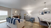 This single-floor, 2-bedroom, 2-bathroom residence offers a thoughtfully designed layout with a comfortable and functional living environment. The living room serves as the heart of the home, highlighted by a classic brick fireplace with a white mantel and a decorative round mirror above it. Light wood-look flooring runs throughout the main living areas, and a sliding glass door opens to a private balcony, allowing natural light to fill the space. A textured ceiling adds character throughout.

The galley-style kitchen is efficiently arranged with gray cabinetry, light countertops, a tile backsplash, and black appliances, including a refrigerator and range, offering a clean, functional cooking space.

The primary bedroom is a well-sized retreat with its own dedicated bathroom. The primary bath features a dual-sink vanity with light stone-look countertops, gray cabinetry, and wood-look flooring. A second bedroom with carpet flooring, a ceiling fan, and a window offers flexibility as a bedroom or home office. The second bathroom is compact and clean with a shower-tub combination. Both bedrooms are accompanied by dedicated closets, providing ample storage throughout the residence.