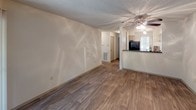 Located at 1300 Longcreek Dr in Columbia, South Carolina, this single-floor residence offers a well-organized layout with a variety of practical features throughout. The main living area is finished with wood-style plank flooring and neutral white walls, creating a clean, open atmosphere. A ceiling fan overhead adds comfort, while a breakfast bar connects the living space to the kitchen, enhancing the open flow between rooms. The kitchen is equipped with dark laminate countertops, light-toned cabinetry, a black electric range with overhead ventilation, and ample counter space for everyday meal preparation. A secondary room features the same wood-style flooring alongside built-in shelving units and a recessed cabinet nook with a dark countertop, offering versatile storage and display options. The bedroom is carpeted for warmth and comfort, and includes a ceiling fan and sliding glass doors that open to an outdoor balcony area, filling the room with natural light. The bathroom is well-appointed with a wide vanity topped with dark counters, a large mirror with overhead lighting, generous under-sink cabinetry, and a bright window that brings in abundant natural light. Textured ceilings are consistent throughout, and recessed lighting adds subtle illumination to key areas of the home.