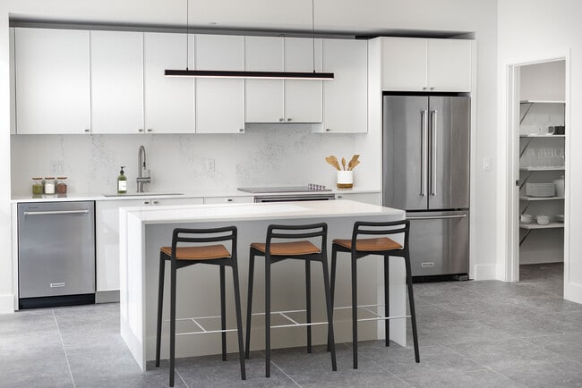 Signature Collection Townhome kitchen with white cabinetry, white marbled quartz countertop and backsplash, wine fridge, and upgraded stainless steel appliances - Avalon South Miami Apartments