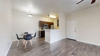 Located at 1900 Aquarena Springs Dr in San Marcos, TX, this single-floor, 3-bedroom, 2-bathroom home offers a practical and well-appointed layout. The open-concept living, dining, and kitchen area forms the heart of the home, featuring durable wood-look flooring, crown molding, and a ceiling fan with light fixture. The kitchen is equipped with stainless steel appliances — including a refrigerator, range, and microwave — rich dark-brown cabinetry, a tile backsplash, and a peninsula with an integrated sink that doubles as a breakfast bar. The dining area comfortably accommodates a table and chairs beneath a pendant light. Two of the three bedrooms are finished with plush carpet and ceiling fans, each featuring a window that brings in natural light. The third bedroom features wood-look flooring. The bathrooms include dark-wood vanities with light countertops, wood-look tile flooring, and a full tub-shower combination. A dedicated laundry room provides washer and dryer hookups with overhead shelving. Five closets throughout the home offer generous storage. The covered patio provides outdoor seating and views of the surrounding tree-lined neighborhood. A hallway connects the private quarters seamlessly to the main living space.