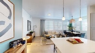This 2-bedroom, 2-bathroom single-floor residence offers a cohesive and modern design throughout, highlighted by light hardwood-style flooring, a neutral color palette, and an abundance of natural light streaming through large windows dressed with white blinds and linen drapes.

The open-concept kitchen is a standout feature, boasting gray shaker cabinetry, white quartz countertops, a classic subway tile backsplash, stainless steel appliances, a center island, and pendant lighting — all flowing seamlessly into the combined dining and living areas. The living room is bright and welcoming, with large windows and direct connectivity to the dining space, making it ideal for entertaining.

A teal-accented hallway with crisp white panel doors connects the living areas to the private quarters, adding a pop of curated color. The primary bedroom is a comfortable retreat with a spacious walk-in closet featuring multi-tier shelving and hanging rods. Both bathrooms are finished in white with gray cabinetry, quartz countertops, full tub-shower combinations, and large mirrors with vanity lighting.

Additional closets and hallway storage add practical functionality throughout. The overall ambiance is clean, modern, and inviting — a well-balanced space designed for comfortable everyday living.