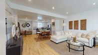 This two-floor residence is designed with a clean, contemporary aesthetic that emphasizes open, light-filled spaces throughout. The main level centers on an open-concept layout where the living room, dining area, and kitchen flow seamlessly into one another. Light wood-tone flooring runs continuously across this level, enhancing the sense of openness. The kitchen is well-appointed with white shaker cabinetry, gray countertops, and a full suite of stainless steel appliances, including a gas range, microwave, and french-door refrigerator. Recessed lighting illuminates the space evenly overhead.

The living area is generously proportioned, with recessed lighting and windows that allow natural light to filter in. A staircase connects the two floors, leading to the upper level where bedrooms feature soft neutral carpet, natural light through blinded windows, and ceiling fans. Closet space is provided with built-in rod systems. Bathrooms on both levels are finished consistently with white cabinetry, gray countertops, wood-look flooring, and tub-shower combinations with clean white surrounds. The overall palette of white walls and neutral tones gives the home a bright, cohesive ambiance throughout.