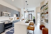 Located in the heart of Charlotte's Morehead Street corridor, this thoughtfully designed one-bedroom, one-bathroom residence offers a sleek, modern living experience across a single floor. The open-concept kitchen and living area serves as the centerpiece of the home, featuring slate-gray cabinetry with gold hardware, stainless steel appliances, a white waterfall island with bar seating, and pendant lighting — all set against light wood-style flooring and crisp white walls. Floor-to-ceiling windows and a glass-panel door flood the living room with natural light and provide direct access to a private balcony with urban views of the surrounding cityscape. The spacious bedroom offers large windows framing city views, ample natural light, and a well-organized walk-in closet with built-in shelving and hanging storage. The bathroom features large-format gray tile flooring, a glass-enclosed walk-in shower with white subway tile, and a dark navy vanity with gold-accented hardware. Additional spaces include a dedicated laundry area and a utility room, enhancing everyday functionality. Clean lines, contemporary finishes, and abundant natural light define the overall ambiance of this urban residence.
