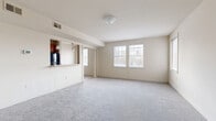 Located at 49 Shipping Pl in Dundalk, MD, this single-floor, one-bedroom, one-bathroom unit offers a well-organized and functional layout. The living area is carpeted throughout and bathed in natural light from large multi-pane windows that frame views of the surrounding neighborhood. Neutral, warm-toned walls and flush-mount ceiling lighting give the space a clean, understated aesthetic.

A defining feature of the living area is the pass-through kitchen opening, which connects the cooking space to the main living room. The kitchen is equipped with warm wood-toned cabinetry, a built-in microwave, a refrigerator, and pendant lighting above the pass-through counter, creating an efficient and inviting culinary space.

The generously sized bedroom continues the carpeted flooring and light-toned walls, with multiple windows allowing ample natural light to fill the room. A dedicated closet provides practical storage, keeping the bedroom area clean and uncluttered.

The bathroom features tile flooring, a full tub-shower combo with white tile surround, a toilet, and a vanity with rich wood-toned cabinetry and a light countertop. The layout is compact yet complete, offering all essential amenities. Overall, this unit presents a bright, functional living environment with a cohesive, neutral design palette throughout.